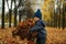 Adorable three year old caucasian boy wearing warm blue jacket and hand knit beanie standing on the lane in a park with a heap of