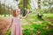 Adorable three year old girl in pink dress enjoying sunny spring day in Park of Sceaux near Paris