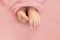 Adorable tine baby girl feet on soft pink background, maternity and babyhood concept