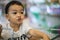 An Adorable toddler Asian boy 1-year-old sitting and play inside the trolley with blurry supermarket background