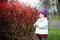 Adorable toddler in barberry bushes on autumn day