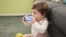 Adorable toddler bitting plastic hoop sitting on floor at home