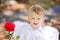 Adorable toddler boy in angel costume holding red rose