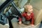 Adorable toddler boy playing in the driver`s seat. Cute little son sitting in fathers car