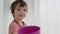 Adorable toddler boy plays with purple cup by white curtain