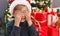 Adorable toddler covering eyes with hands standing by christmas tree at home