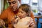 Adorable toddler enjoys eating popsicle ice cream on parent`s lap