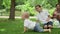 Adorable toddler falling on grass in park. Parents laughing with kids outdoors