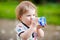 Adorable toddler girl drinking formula milk or water from bottle. Cute happy baby child walking outdoors. Thirsty baby.