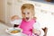 Adorable toddler girl eating healthy vegetable meal with potatoes and carrots soup for lunch. Cute happy baby child