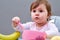 Adorable toddler girl is having fun while eating on greyish background