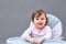 Adorable toddler girl is having fun while eating on greyish background