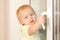 Adorable toddler girl holding window knob