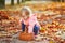 Adorable toddler girl picking chestnuts in Tuileries garden in Paris, France