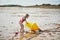 Adorable toddler girl playing on the sand beach near large yellow buoy at Atlantic coast of Brittany, France