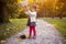 adorable toddler girl playing sunny autumn prak. cute baby girl pours autumn yellow leaves from a basket on forest path