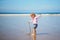 Adorable toddler girl playing with weeds on the sand beach at Atlantic coast of Brittany, France