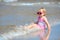 Adorable toddler girl splashing in ocean waves
