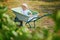 Adorable toddler girl in straw hat sitting in wheelbarrow on a farm