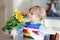 Adorable toddler girl and sunflower. Cute child holding big blooming flower.