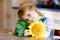 Adorable toddler girl and sunflower. Cute child holding big blooming flower.