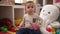 Adorable toddler holding car toy sitting on floor at home