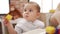 Adorable toddler holding plastic construction blocks sitting on table at kindergarten