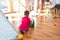 Adorable toddler playing bowling around lots of toys at kindergarten