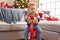 Adorable toddler playing on reindeer rocking by christmas tree at home