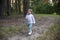 Adorable toddler walks in the woods park in summer sunny day