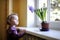 Adorable toddler by the window with the flowers