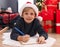 Adorable toddler writing on notebook lying by christmas tree at home