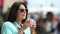 Adorable tourist young woman smiling drinking coffee outdoor enjoying cityscape medium close-up