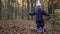 Adorable two years old girl twirl under falling leaves in autumn forest