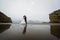 Adorable wedding couple walking along the beach, reflecting in the water. Panoramic view