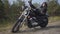 Adorable young caucasian woman in a black leather jacket and pants lying on a classic motorcycle. Hobby, traveling and