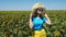 Adorable young girl in a straw hat, yellow skirt and blue t-shirt in sunflowers field. Lady with long blonde hair 4K