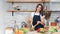 Adorable young vegan woman mixing fresh appetizing salad in bowl posing in kitchen at home