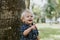 Adorably Happy and Cute Little Caucasian Toddler Baby Boy with Long Blond Hair Laughing, Playing, and Running Outside in Green Nat