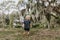 Adorably Happy and Cute Little Caucasian Toddler Baby Boy with Long Blond Hair Laughing, Playing, and Running Outside in Green Nat