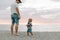 Adorably Perfect Young Father and Baby Toddler Son Family Having Fun Time at the Sandy Beach During Sunset Outside By the Ocean Wa