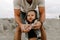 Adorably Perfect Young Father and Baby Toddler Son Family Having Fun Time at the Sandy Beach During Sunset Outside By the Ocean Wa