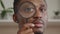 An adult african american man is looking through a magnifying glass into the camera