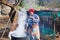 Adult african woman in traditional blanket dress brews national drink in metal barrel at village courtyard in Lesotho, Africa