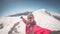 Adult alpin skier with beard, sunglasses and hat, taking selfie on snowy slope in the beautiful italian Alps with clear blue sky.