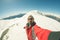 Adult alpin skier with beard, sunglasses and hat, taking selfie on snowy slope in the beautiful italian Alps with clear blue sky.