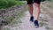 Adult athlete in blue sneakers and black shorts walks on the road