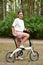 An adult athletic woman is half-sitting on a compact folding bike