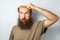 Adult bald male holding hairbrush, suffering alopecia, looking up with confused facial expression.