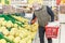 Adult bald man in a medical mask and gloves chooses fruits in a supermarket. Healthy eating and vegetarianism. Self-isolation